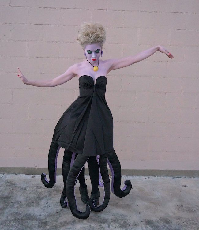 a woman dressed up as an octopus with makeup on her face and hands, standing in front of a brick wall