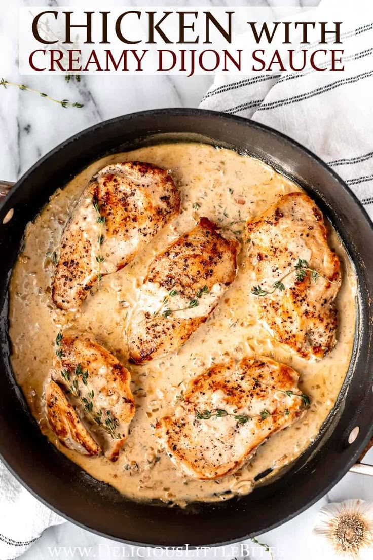 chicken with creamy dijon sauce in a skillet on top of a marble counter