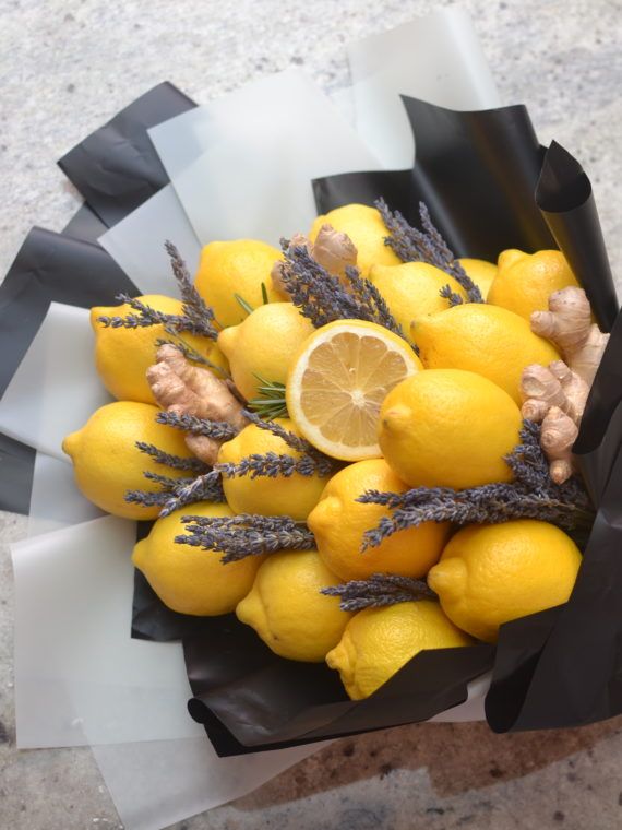 a bunch of lemons and lavender in a black paper bag on a table top