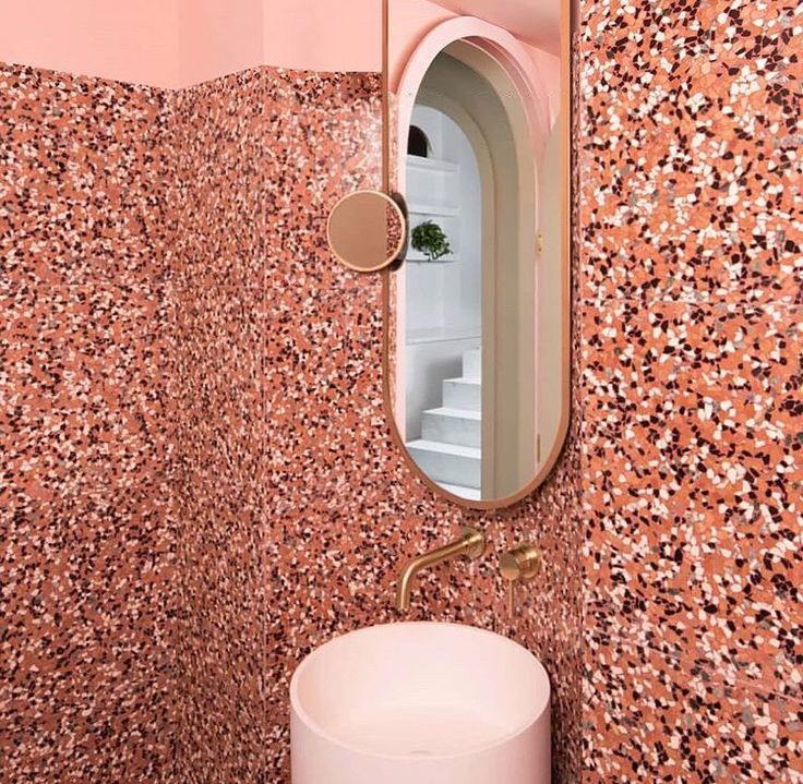 a sink and mirror in a small room with pink wallpaper on the back walls