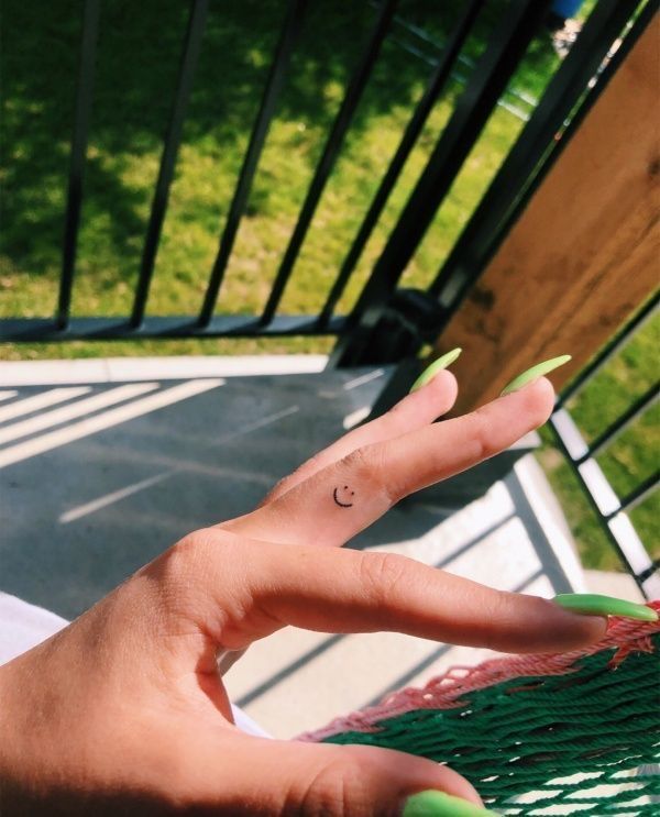 a person's hand with a small tattoo on their left thumb and the middle finger