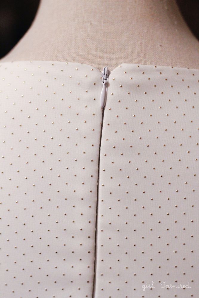 the back of a woman's white dress with gold polka dots and a zipper