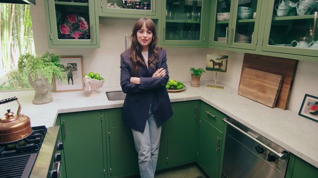 a woman standing in a kitchen with green cabinets