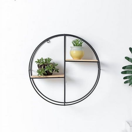 three shelves with plants on them in front of a white wall and a potted plant