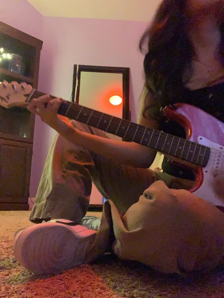 a person sitting on the floor playing an electric guitar