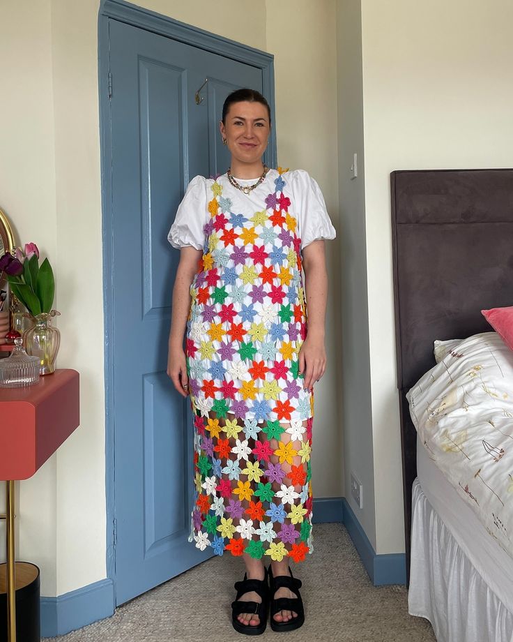 a woman standing in front of a blue door wearing an apron made out of flowers