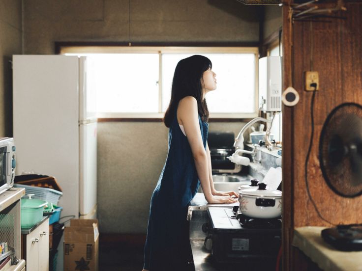 a woman standing in a kitchen next to a stove top oven