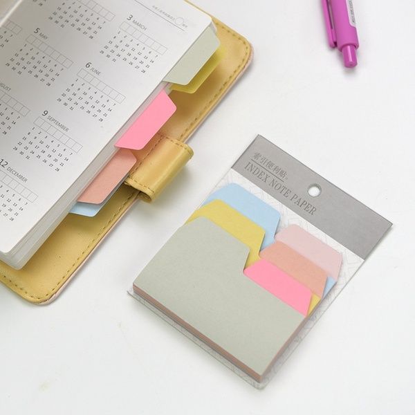 an open planner book with sticky notes attached to it and a pink pen next to it