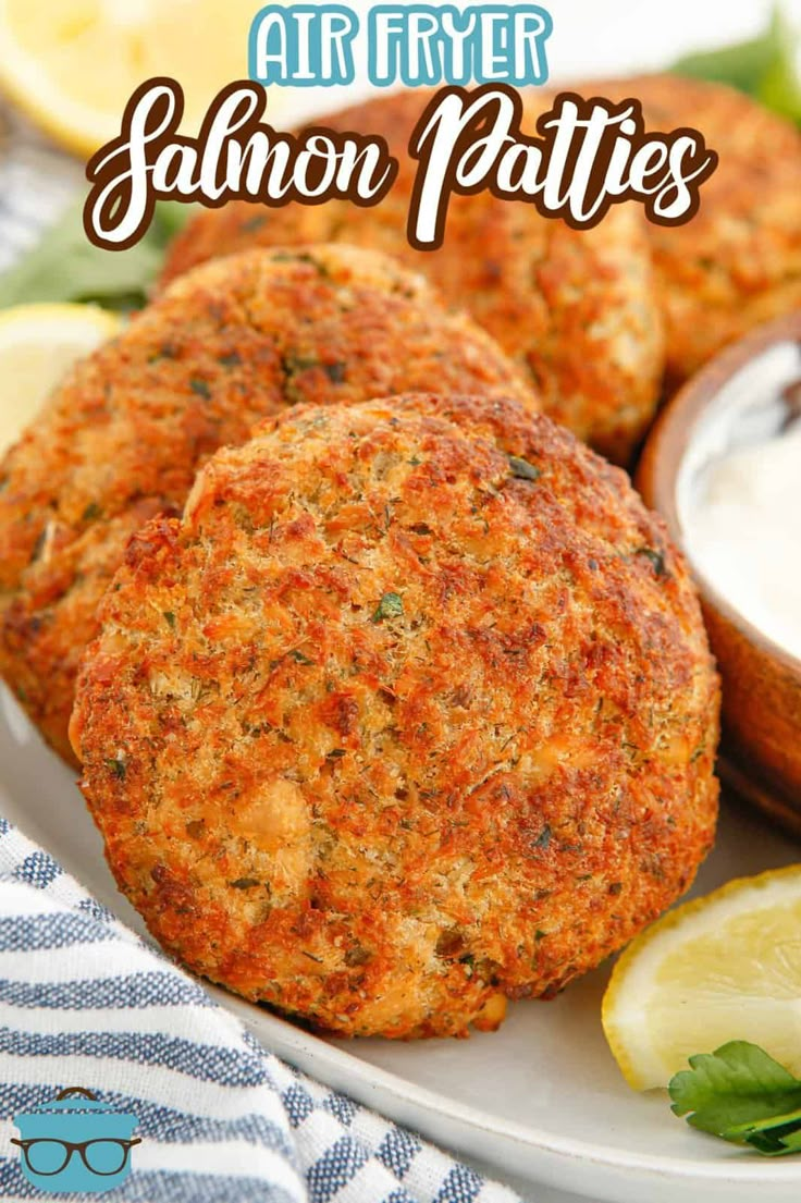 salmon patties on a plate with lemon wedges and ranch dressing in the background