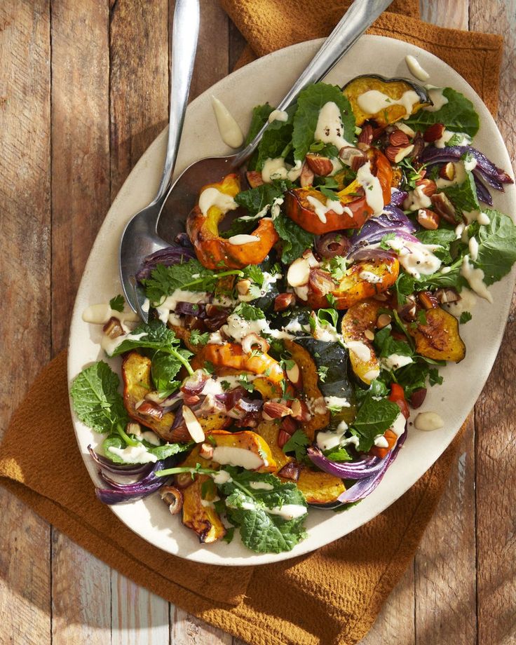 a white plate topped with salad on top of a wooden table next to a fork