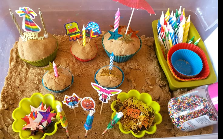 there are many cupcakes in the sand with umbrellas on top and other decorations