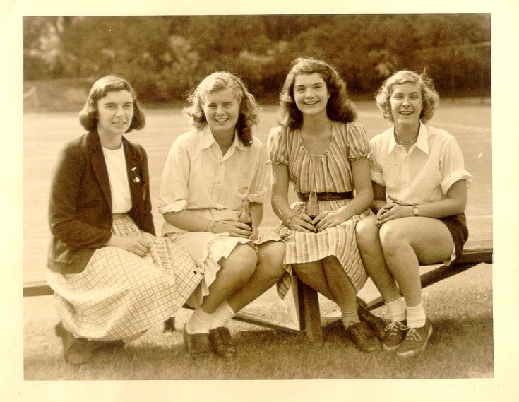 an old black and white photo of four women sitting on a bench