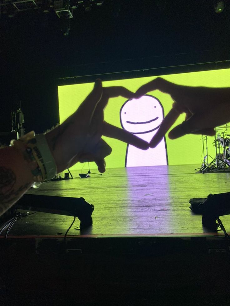 two people holding their hands in front of a large screen with a smiley face on it