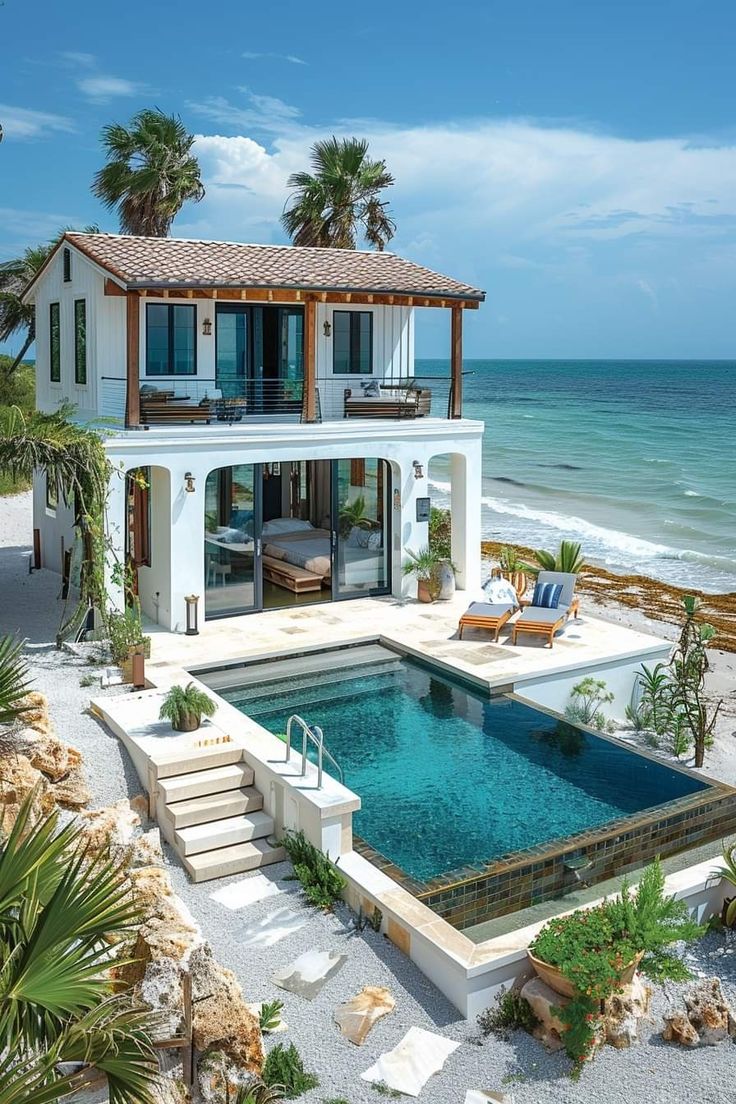 a house on the beach with a swimming pool in front of it and palm trees