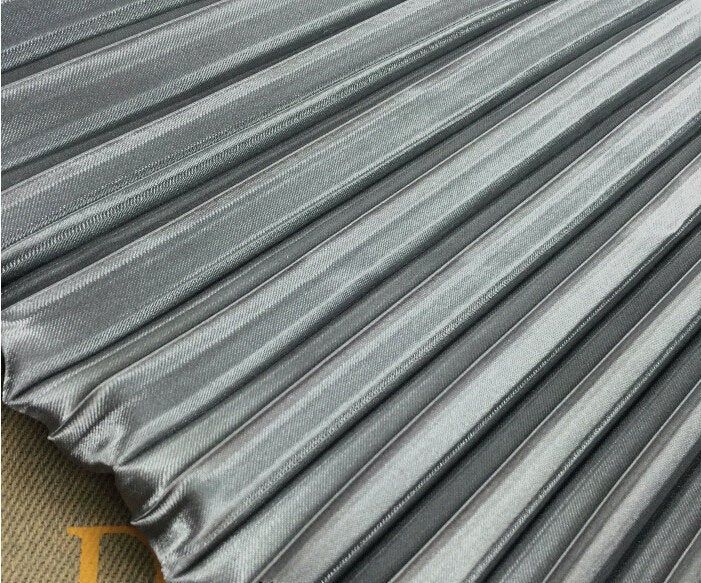 an up close shot of the fabric on top of a bed sheet with silver stripes