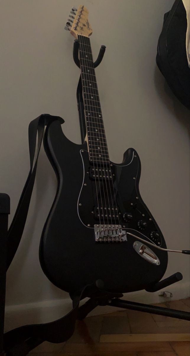 a black guitar sitting on top of a wooden floor