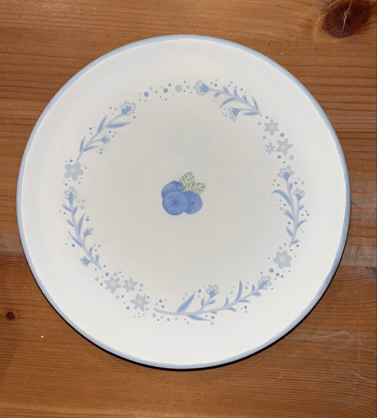 a white plate with blue berries painted on it