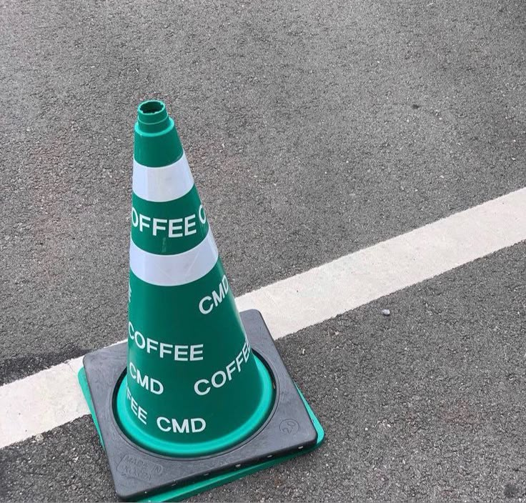 a green and white traffic cone sitting on the ground