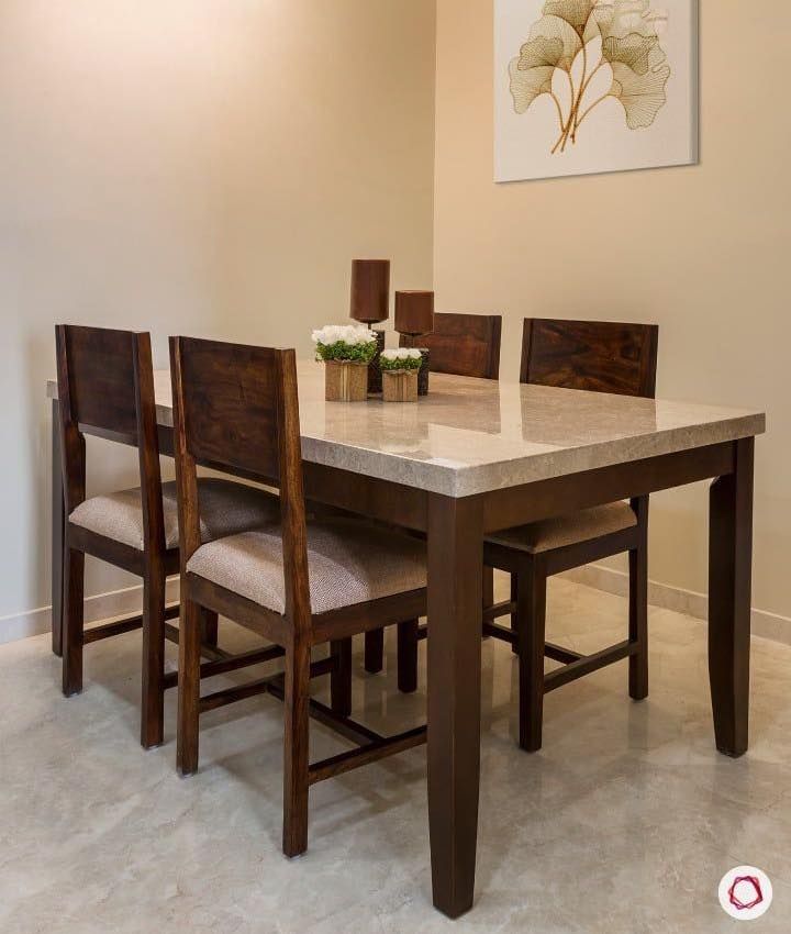 a dining room table with four chairs and a painting on the wall in the background