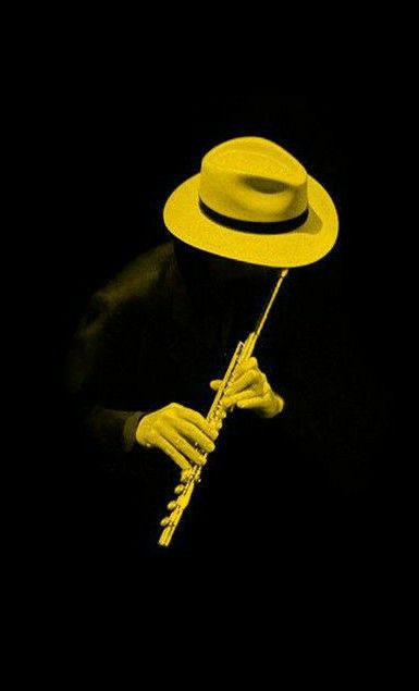 a person wearing a yellow hat and holding a stick with one hand in the dark