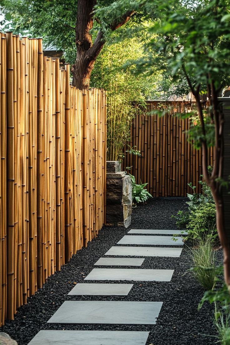 a bamboo fence with stepping stones in the center and trees around it, along with black gravel