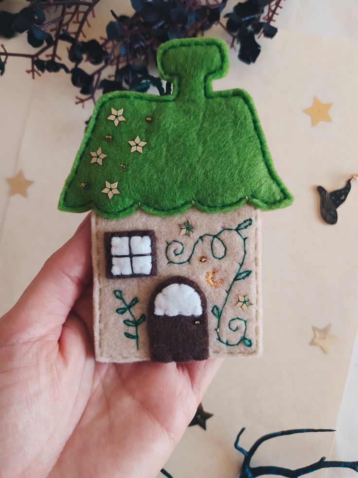 a hand holding a small felt house ornament