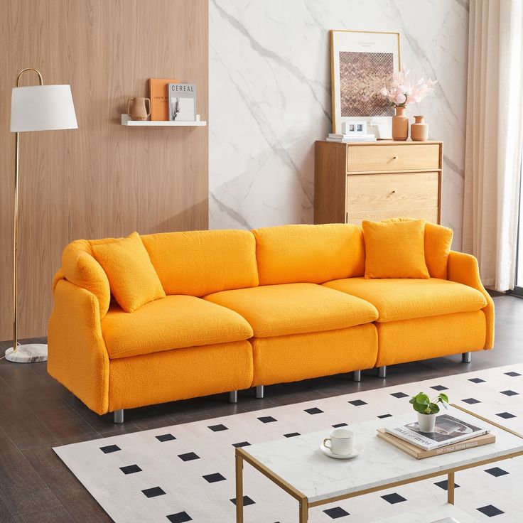 a living room with an orange couch and white rug on the floor next to a coffee table