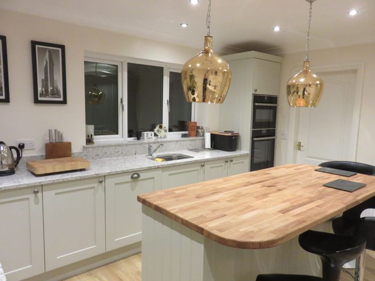 a kitchen with white cabinets and wooden counter tops next to an island in the middle