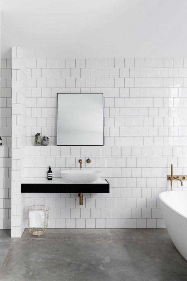 a bathroom with white tiles and black counter tops, along with a large mirror on the wall