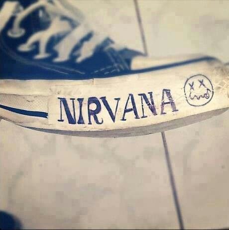 a banana with the word nirvana on it sitting on top of a tile floor next to a pair of shoes