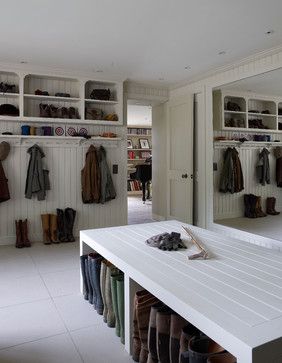 a room filled with lots of coats and shoes on shelves next to a white table