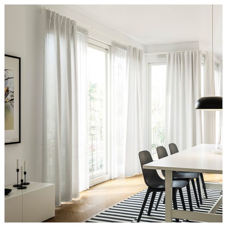 a dining room with white curtains and black chairs