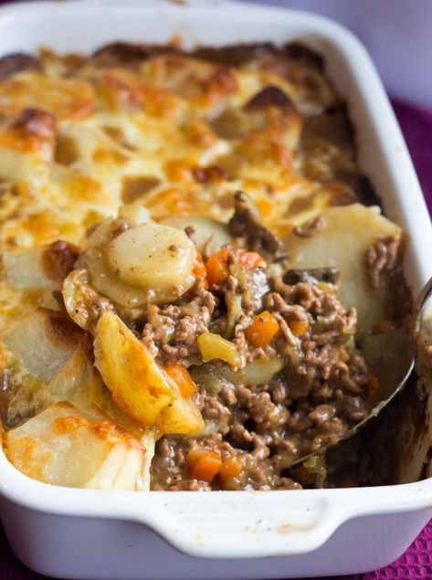 a casserole dish with potatoes and meat in it on a purple table cloth