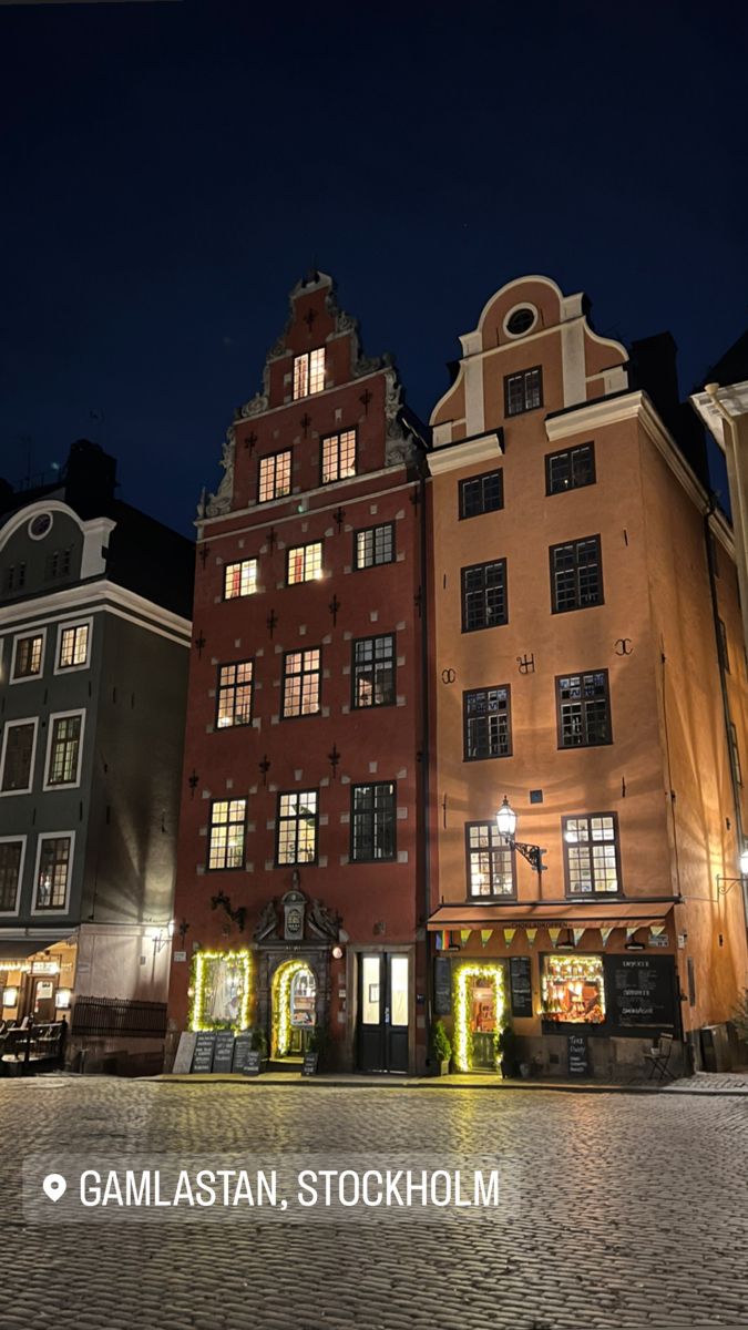 several buildings are lit up at night in the town square with cobblestone streets