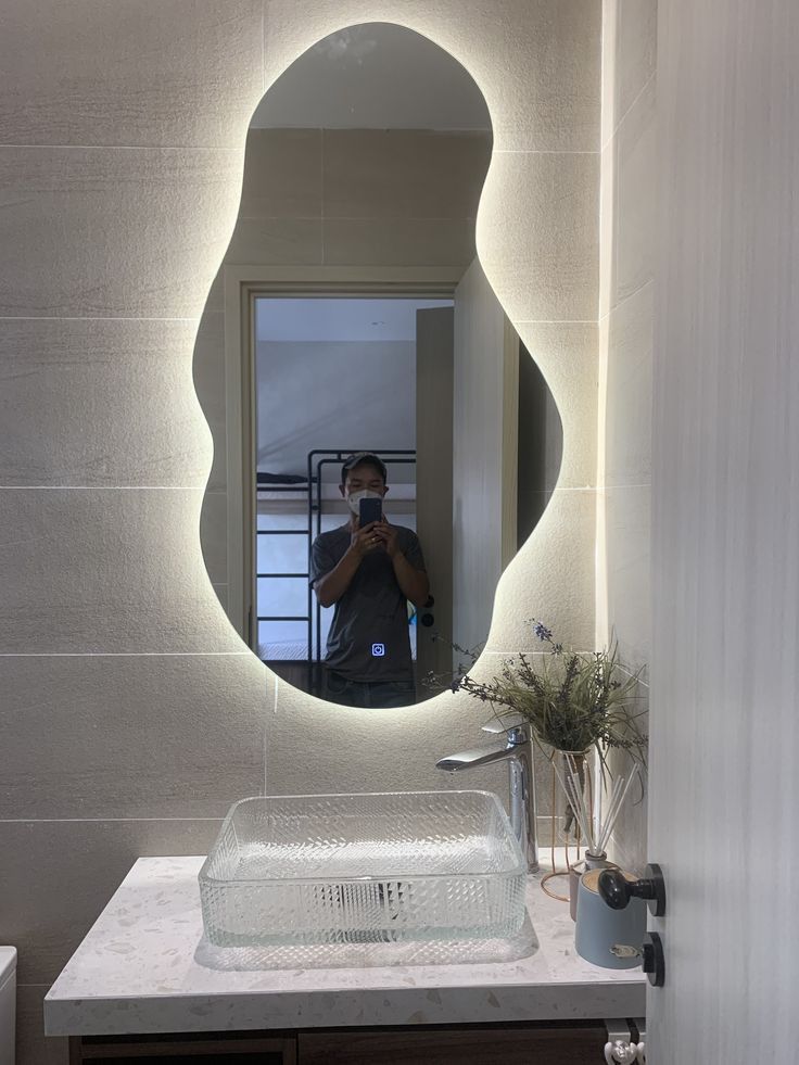 a man taking a photo of himself in front of a bathroom mirror with the light on