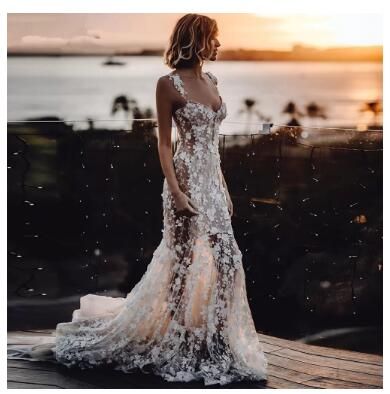 a woman in a white dress standing on a wooden deck near the water at sunset