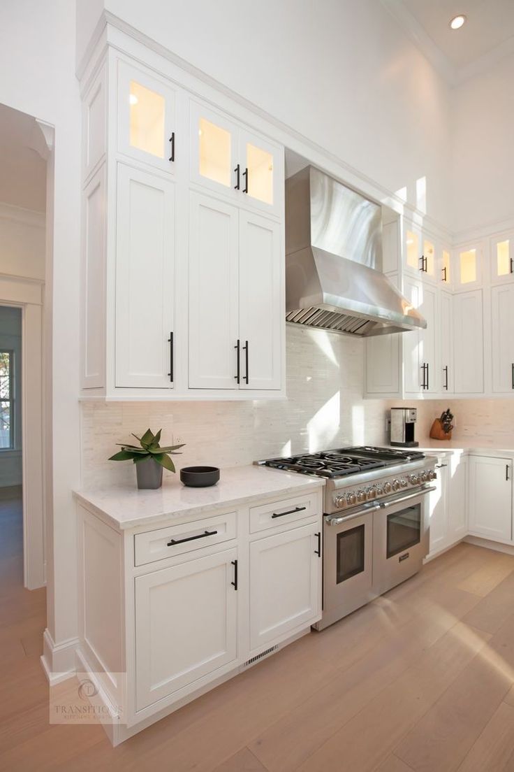 a kitchen with white cabinets and stainless steel stove top oven in the center of the room