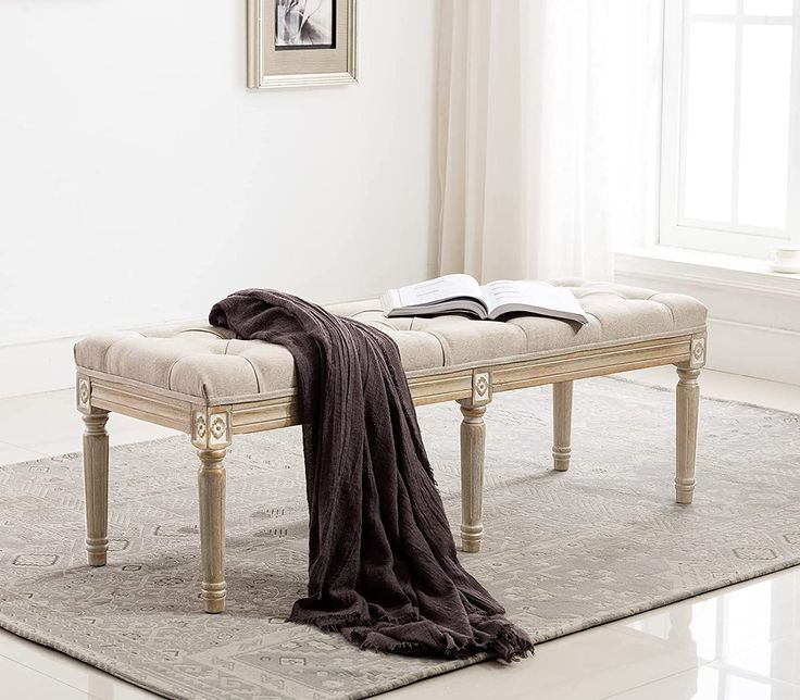 a white bench sitting on top of a rug next to a window