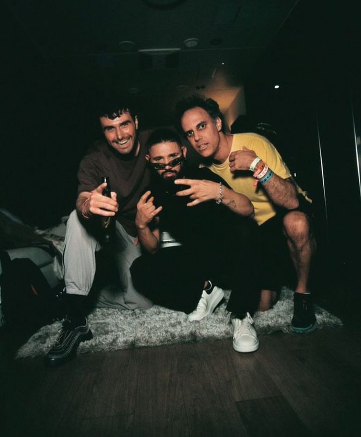 three men posing for a photo in the dark with one pointing his finger at the camera