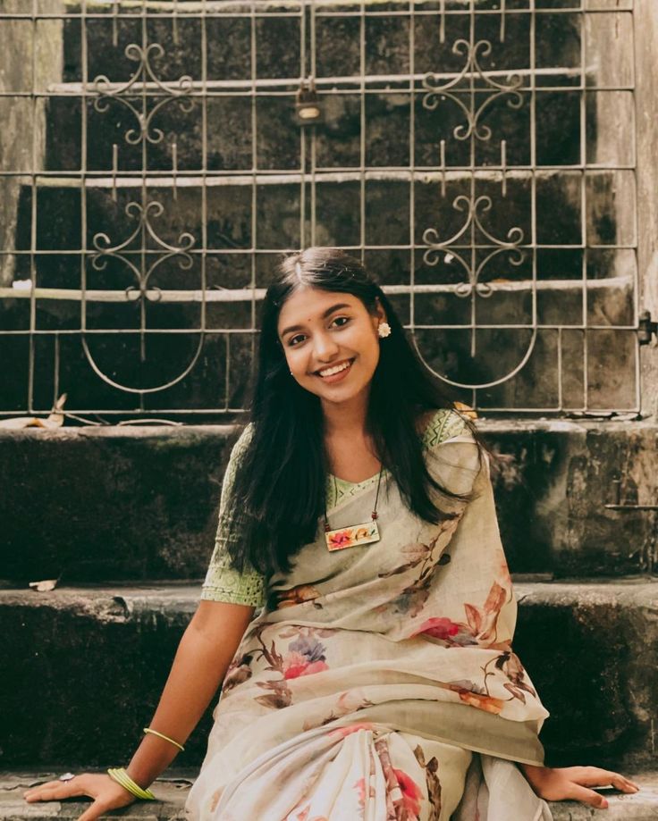 a woman is sitting on the steps in front of some stairs and smiling at the camera