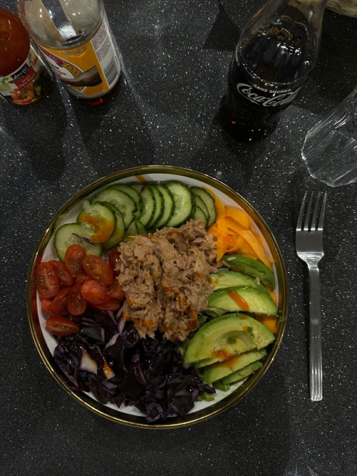 a plate with cucumbers, tomatoes, and other vegetables on it next to a glass of wine