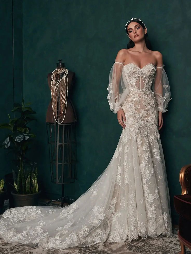 a woman in a wedding dress standing next to a green wall