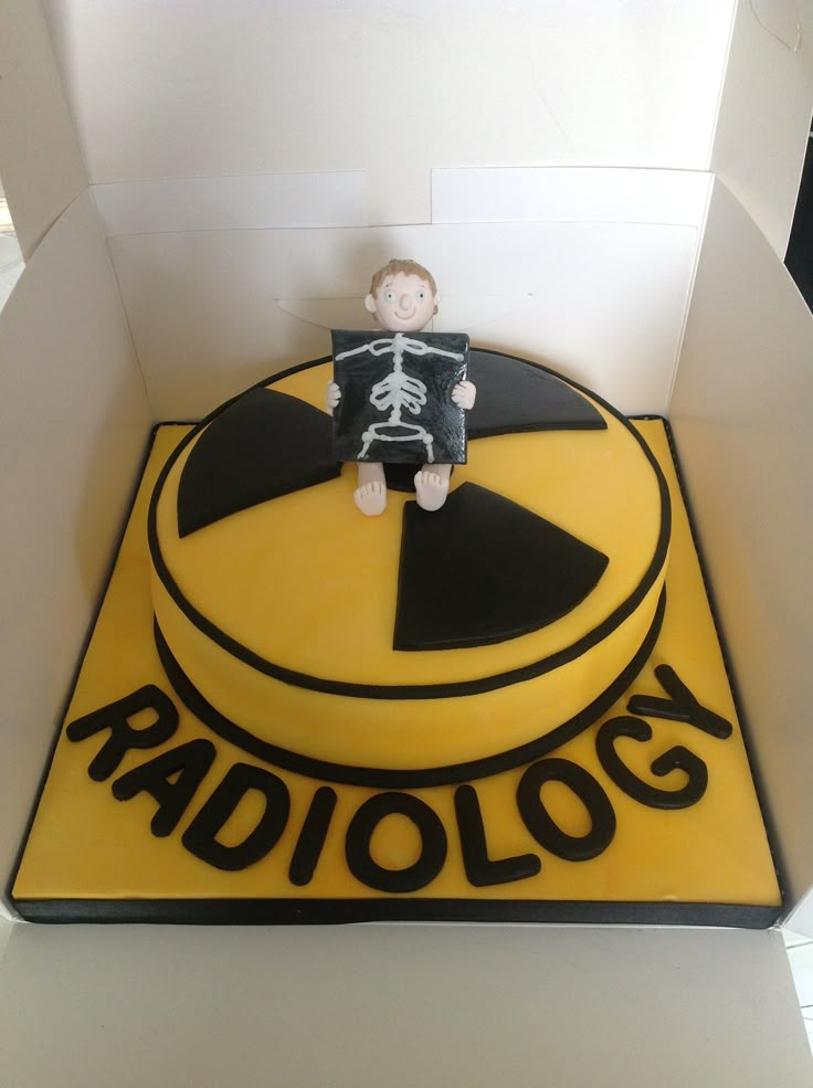 a cake in the shape of a radiology sign with a person sitting on it