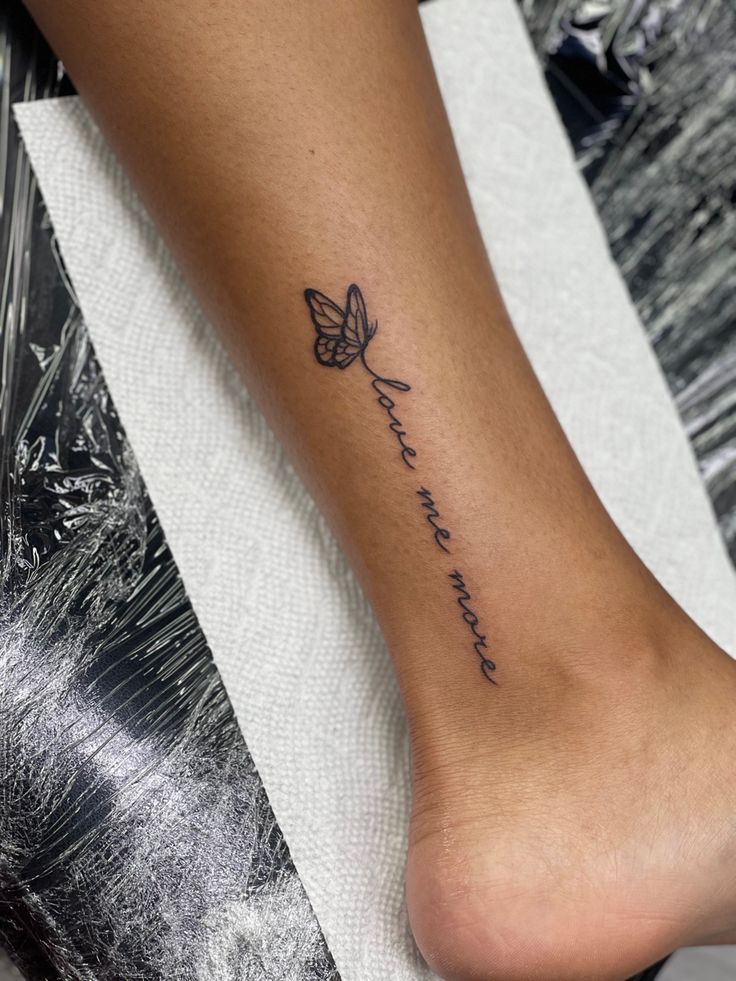 a woman's foot with a small butterfly tattoo on her left leg and the words,