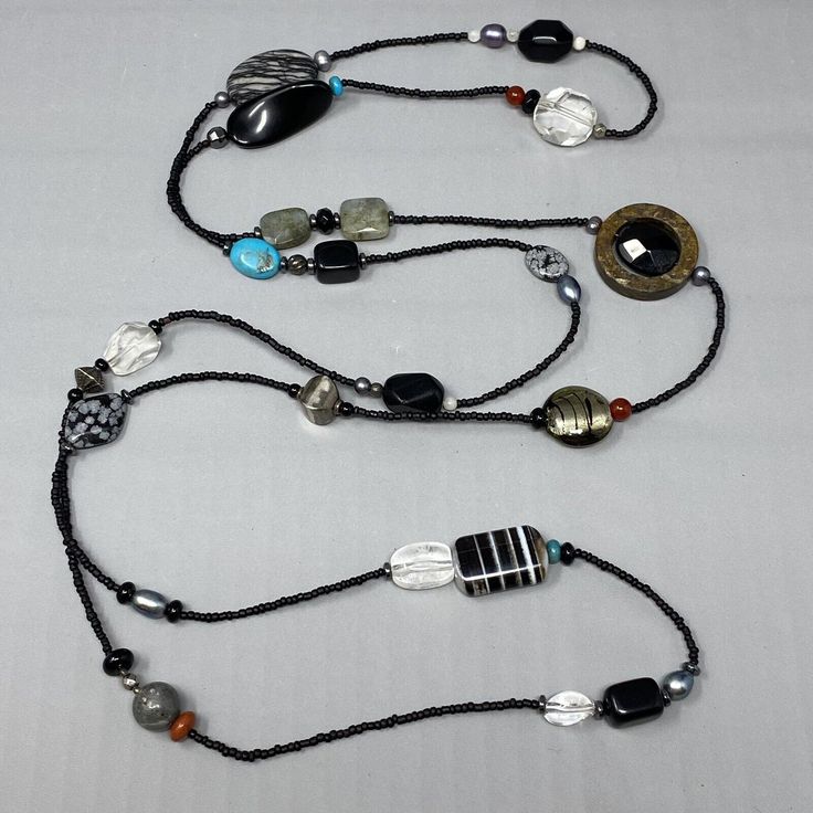 three necklaces with various beads and charms hanging from each side on a white surface