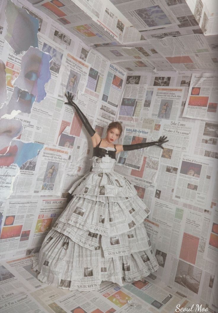 a woman in a white dress and black gloves standing on top of a pile of newspapers