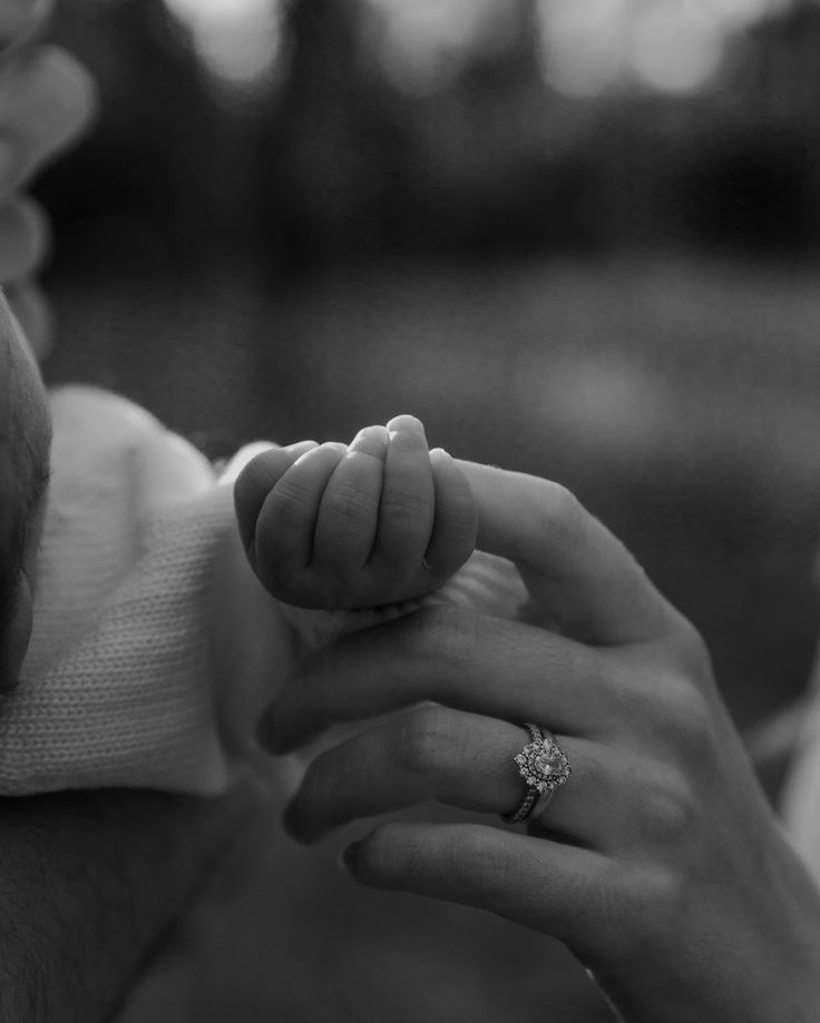 a woman holding a baby's hand while she holds the finger of another person