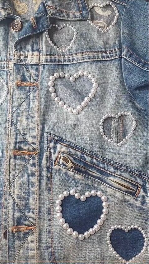 the back of a jean jacket with hearts on it and pearls hanging from the pockets