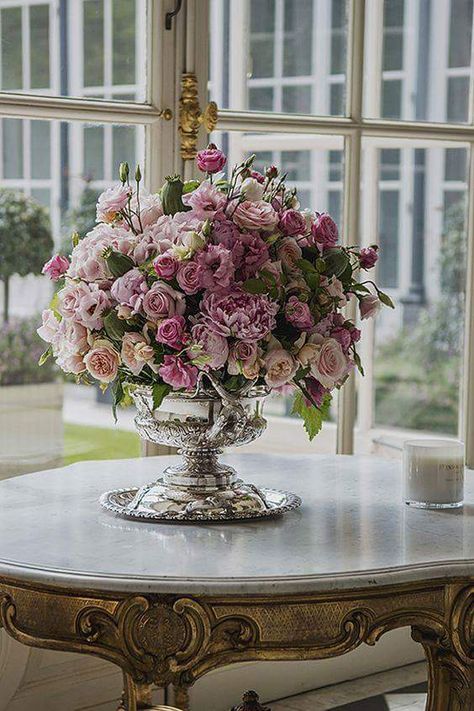 a vase filled with pink flowers sitting on top of a table next to a window