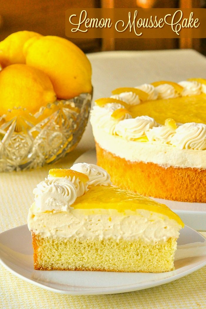 a lemon mousse cake on a white plate next to a bowl of lemons